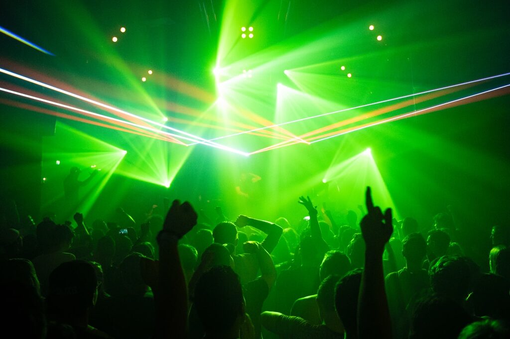 people dancing inside room with green lights EDM music