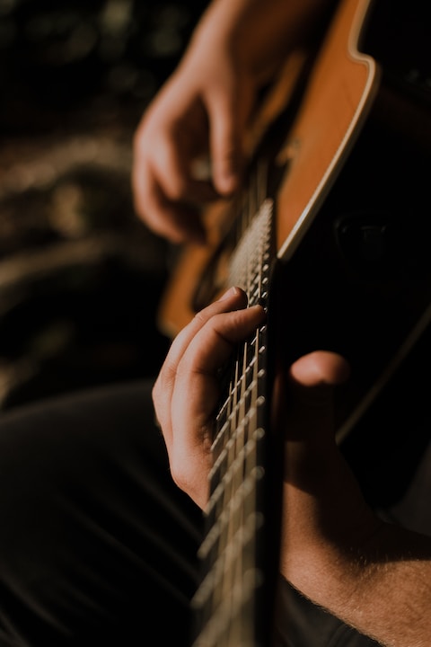 person playing music on acoustic guitar