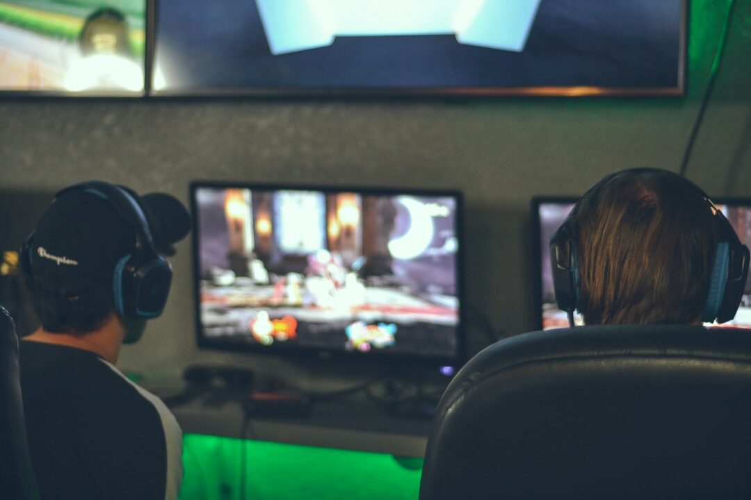 selective focus photography of two persons playing game in front of computer monitors