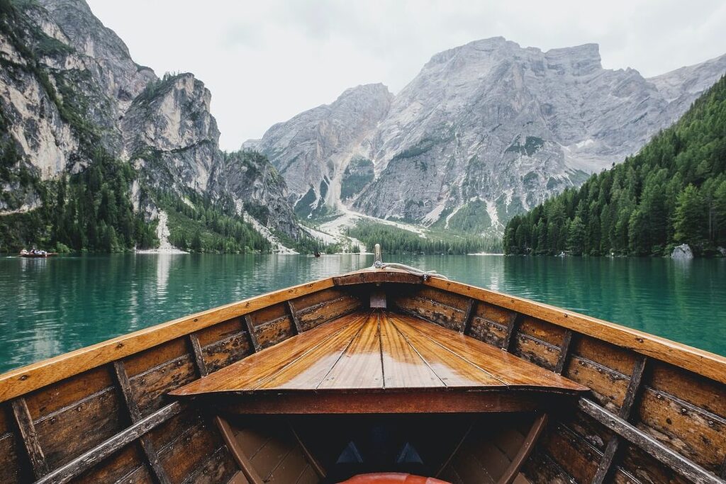 brown wooden boat moving towards the mountain travel