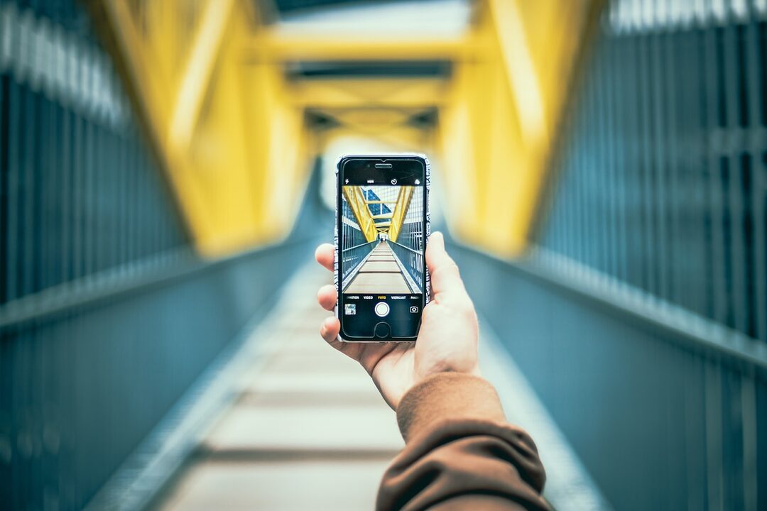 person holding space gray iPhone 6 smartphone taking a photo of a bridge