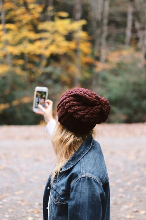 woman taking selfie near trees smartphones