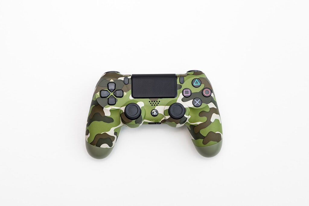 green, black, and white camouflage Sony DualShock 4 wireless controller playstation console